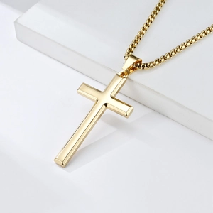 Polished gold stainless steel cross necklace with a beveled edge on a white display