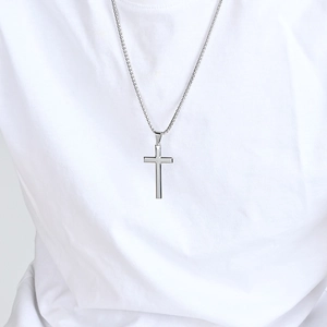 Minimalist stainless steel cross pendant on a box chain worn by a male model