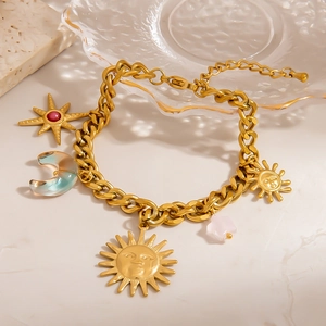 Goldenes Edelstahl-Armband mit Sonnen- und Mondanhängern auf einer Steinfläche präsentiert