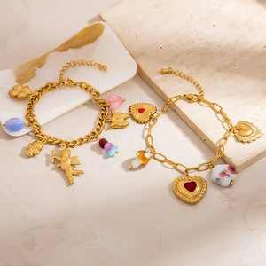 Detailaufnahme goldener Bettelarmbänder mit Cupido-Herz und Sonnenanhängern auf Stein