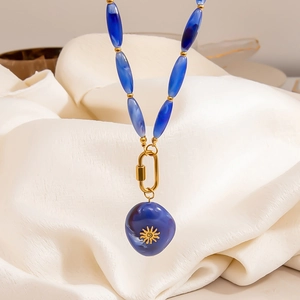 Detail of blue marble beads with golden sun totem pendant and metallic clasp buckle