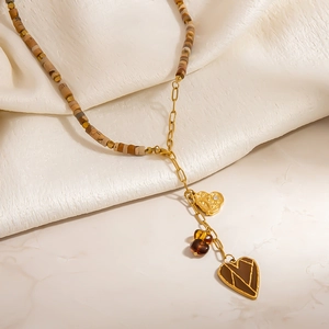 Collier Y bohème en perles avec pendentifs cœurs en acier sur un tissu en soie blanc