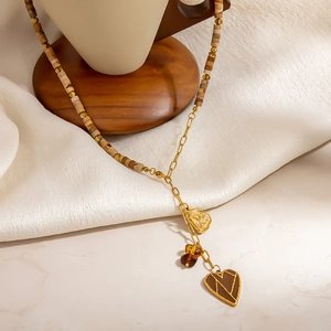 Collier en Y perlé avec pendentifs cœur dorés et perles de pierre marron sur un présentoir