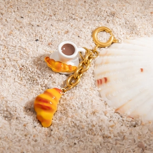 French style gold pastry keychain with mini coffee cup and croissant pendants on sand