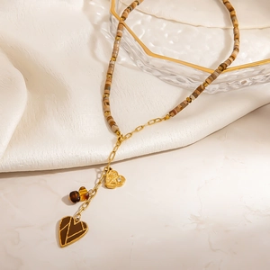 Collier perlé bohème en acier inoxydable avec cœurs marrons sur tissu blanc