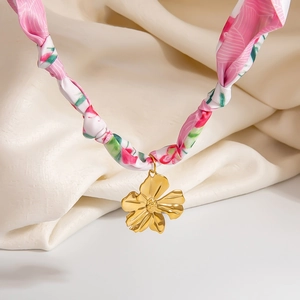 Detail of golden floral pendant on a pink floral print silk ribbon necklace strand