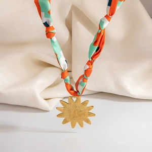 Collana foulard in seta con ciondolo a sole dorato su un elegante sfondo in tessuto