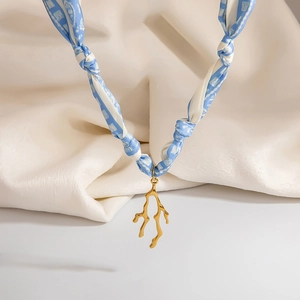 Dettaglio della collana foulard in seta blu e bianca con ciondolo a ramo di corallo