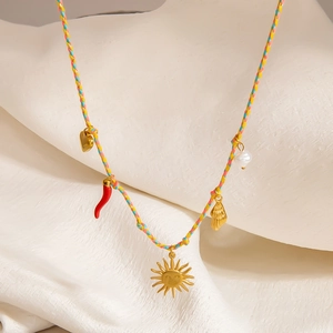 Detail der Bohème-Webkette mit Goldsonne, Muschel- und Perlenanhängern auf einem weißen Ständer