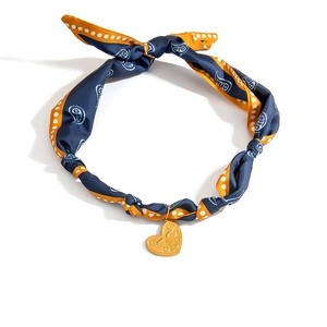 Detailed macro view of heart pendant on blue and orange paisley silk scarf necklace