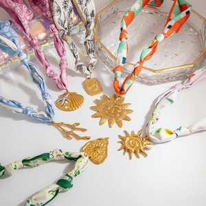 Collana in seta bohémien con grandi ciondoli dorati a cuore e conchiglia su fondo bianco