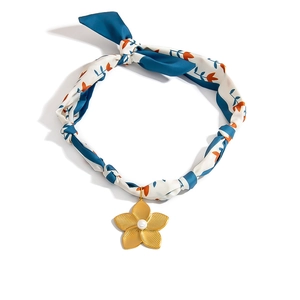 Close-up of gold flower pendant with pearl on a blue floral silk scarf necklace