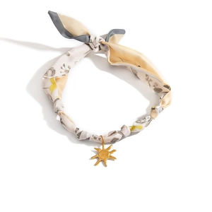 Detail of silk scarf necklace featuring a gold sun pendant with artistic floral pattern