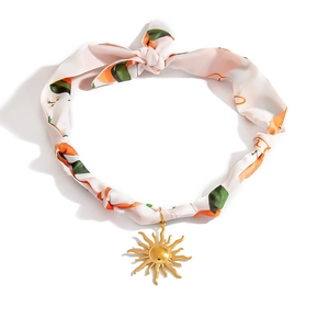 Detail of silk scarf necklace with colorful patterns and golden sun shaped pendant