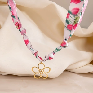 Detalle de collar tipo pañuelo de seda con estampado de tulipanes y flor dorada