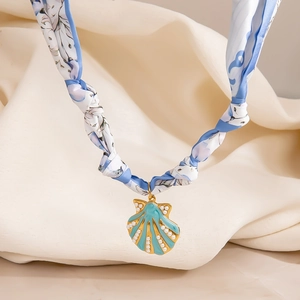Detalle del collar bufanda de seda con colgante de concha en abanico y perlas de adorno