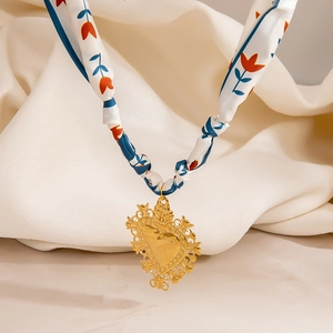 Primer plano del colgante de corazón dorado con elegante pañuelo de seda con flores