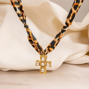 Detalle del collar vintage de seda leopardo con cruz dorada en relieve y piedras claras