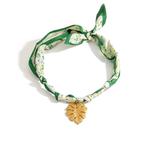 Detalle del colgante de hoja de monstera dorada con cadena de pañuelo de seda floral