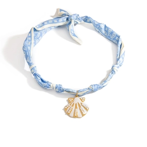 Detalle del collar de pañuelo de seda con colgante de caracola dorada y cuentas blancas