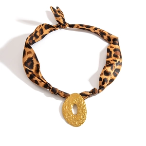 Detailed view of leopard print silk scarf necklace with a gold hammered metal pendant