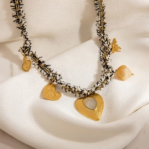 Elegant tweed woven necklace with golden heart and bee charms on white textured background
