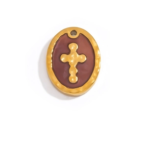 Macro shot of gold-plated oval pendant with relief cross on red enamel background