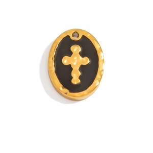 Macro view of vintage oval black enamel pendant with gold cross and hammered texture