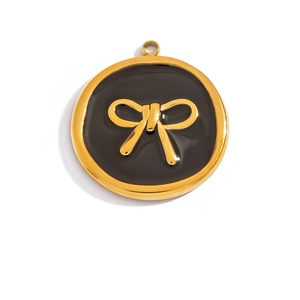 Detailed macro view of a gold-plated circular pendant with black enamel and a 3D bow design
