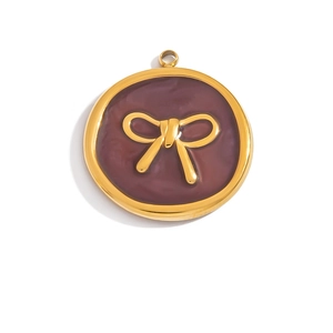 Detailed close-up of a golden round pendant with deep burgundy enamel and a bow tie relief