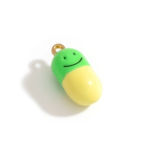 Vue macro d'un pendentif capsule vert et jaune avec un smiley et un anneau doré de détail