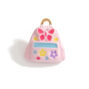 Détail d'une breloque en émail rose en forme de cartable avec motifs de fleurs