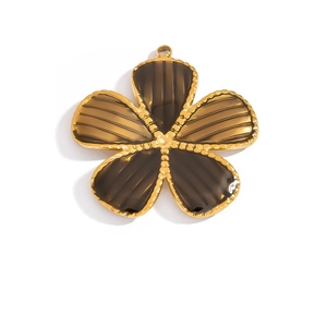 Macro view of gold stainless steel flower pendant with scalloped edges and amber texture