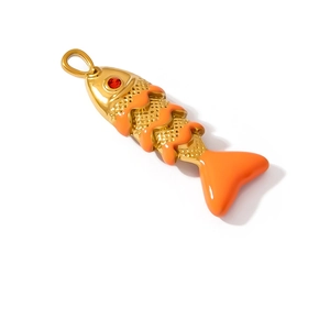 Detail of fish pendant in gold stainless steel with orange enamel scales and red stone