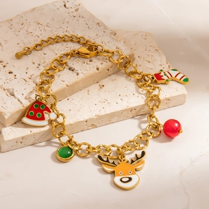 Detail of gold Christmas charm bracelet with Santa hat and reindeer on travertine stone