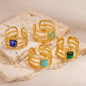 Detailed view of four adjustable hollow rings with inset stones on beige stone
