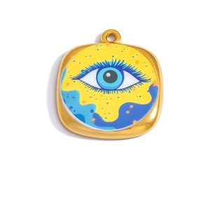 Macro detail of square gold stainless steel evil eye pendant with blue enamel pattern