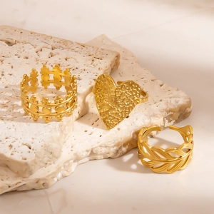 Detailed view of three 18k gold plated stainless steel rings with leaf and heart patterns