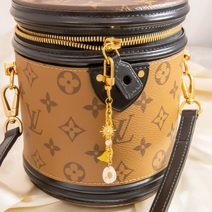 Détail du sac cylindre avec motif monogramme classique et pendentif soleil doré