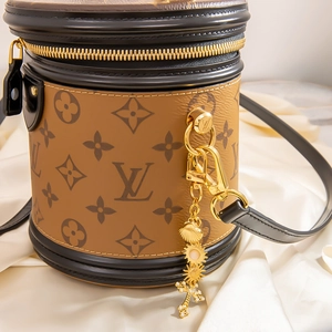 Détails des charms dorés et de la toile monogramme sur le sac seau cylindrique