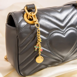 Sac à bandoulière en cuir noir avec matelassage en cœur et pendentif doré serti