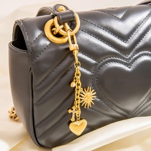 Détails d'un sac en cuir noir matelassé avec des breloques dorées de luxe et soleil