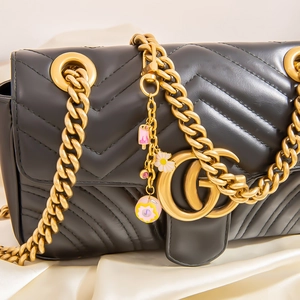 Détail d'un sac à bandoulière en cuir noir matelassé avec chaîne dorée et breloques