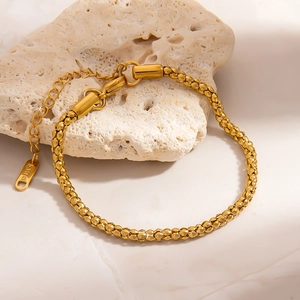 Élégant bracelet chaîne pop-corn en acier plaqué or 18 carats sur une pierre texturée