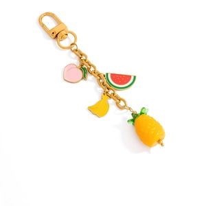 Détail d'un porte-clés doré 18K avec des breloques de fruits colorés comme l'ananas et la pêche