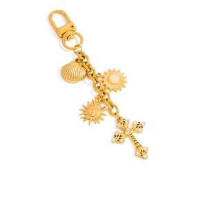 Détail de breloques plaquées or 18 carats avec coquillage, soleil et croix en strass sur chaîne