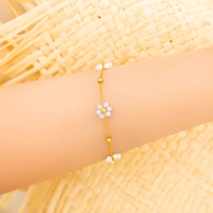Détail macro du bracelet fleuri plaqué or 18K avec perles bleues et blanches élégant