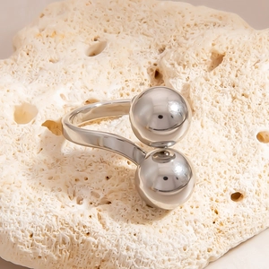 Macro shot of minimalist silver stainless steel ring with two smooth spheres on coral stone