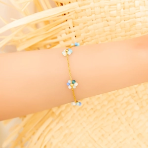 Détail d'un bracelet plaqué or 18K avec fleurs en perles bleues et blanches sur mannequin