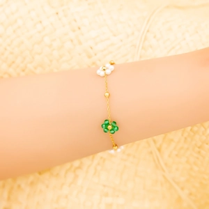 Détail du bracelet chaîne plaqué or avec perles de fleurs colorées tissées à la main